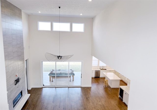 unfurnished living room featuring hardwood / wood-style flooring, plenty of natural light, a fireplace, and a high ceiling