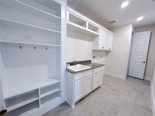 interior space with white cabinetry and sink