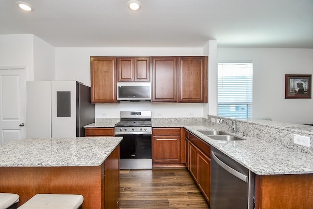 kitchen featuring dark wood-type flooring, sink, a breakfast bar area, stainless steel appliances, and light stone countertops