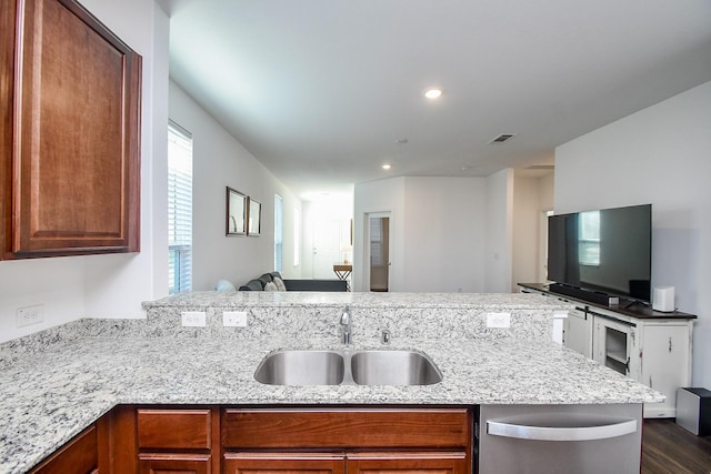 kitchen featuring dark wood-type flooring, sink, light stone counters, kitchen peninsula, and dishwasher