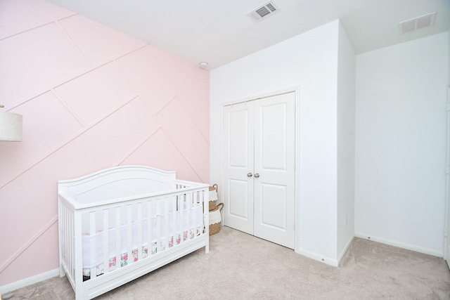 bedroom featuring a nursery area, light colored carpet, and a closet