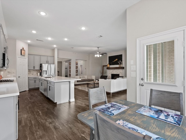 dining area with dark hardwood / wood-style flooring, ceiling fan, a fireplace, and sink