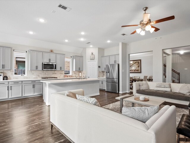 living room with ceiling fan, sink, and dark wood-type flooring