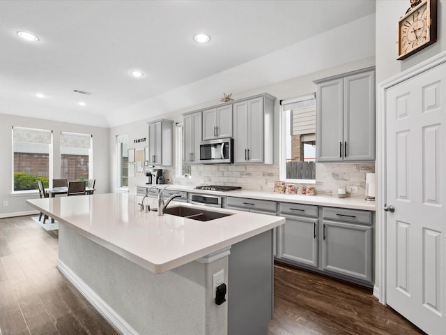 kitchen featuring stainless steel appliances, gray cabinets, a kitchen island with sink, and sink