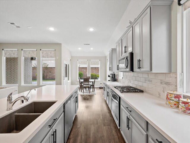 kitchen with sink, tasteful backsplash, dark hardwood / wood-style flooring, gray cabinets, and appliances with stainless steel finishes