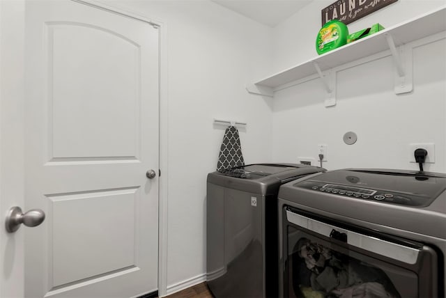 clothes washing area with dark hardwood / wood-style flooring and washer and dryer