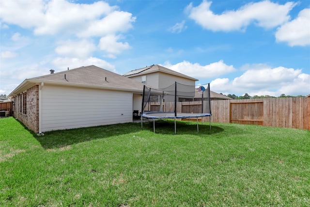 back of property with a yard, a trampoline, and central air condition unit