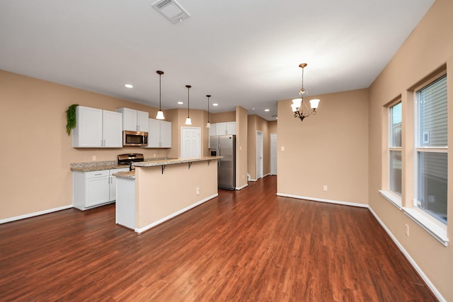 kitchen featuring stainless steel appliances, a kitchen island, pendant lighting, a breakfast bar, and white cabinets