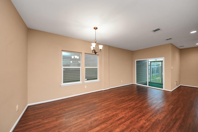 spare room with dark hardwood / wood-style floors and a chandelier