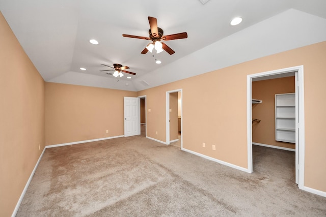 unfurnished bedroom with ceiling fan, lofted ceiling, a walk in closet, a closet, and carpet