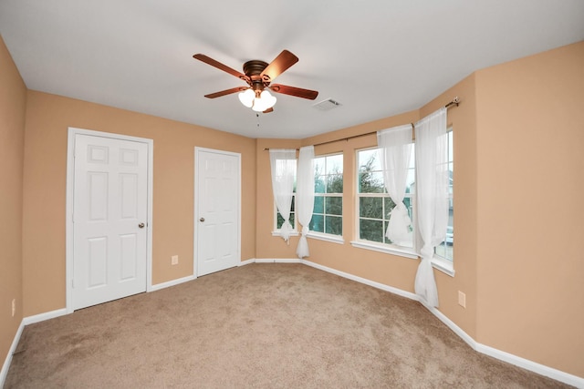 interior space with light colored carpet, ceiling fan, and multiple closets