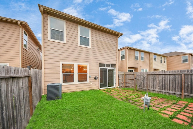 rear view of house featuring central AC unit and a yard