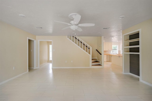 unfurnished room featuring ceiling fan, built in features, and sink