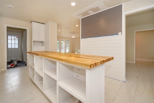 kitchen featuring ceiling fan, white cabinetry, and butcher block counters