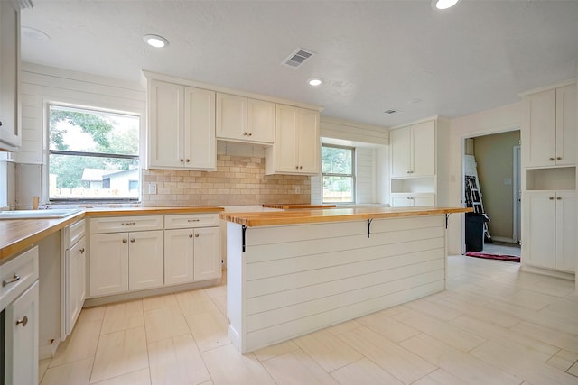 kitchen featuring wood counters, decorative backsplash, white cabinetry, and sink