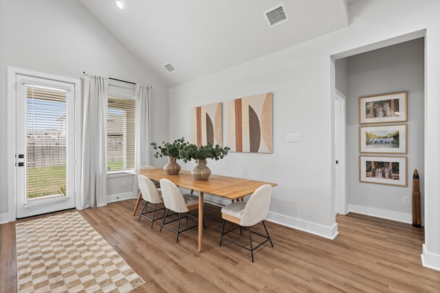 dining room with light hardwood / wood-style flooring and high vaulted ceiling