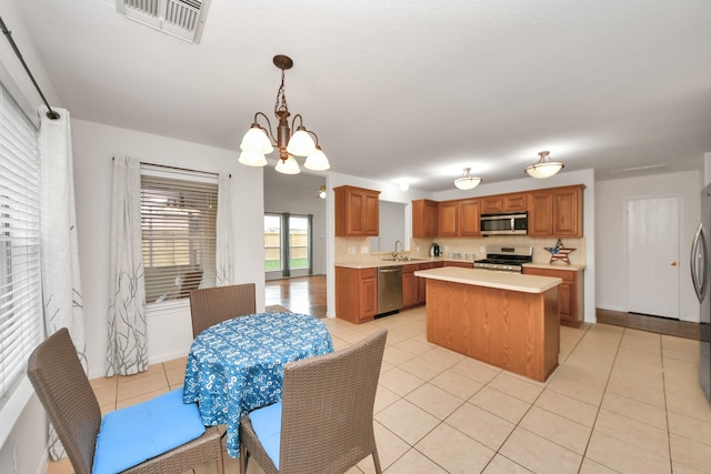 kitchen with sink, a center island, hanging light fixtures, a notable chandelier, and stainless steel appliances