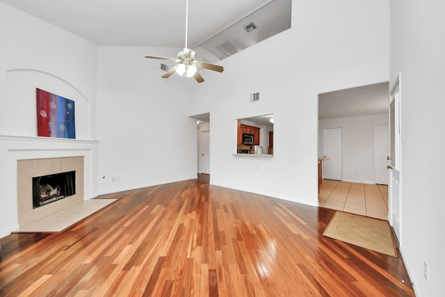 unfurnished living room with ceiling fan, wood-type flooring, a fireplace, and high vaulted ceiling