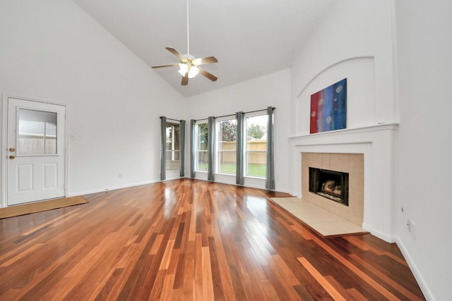 unfurnished living room with a tiled fireplace, ceiling fan, hardwood / wood-style flooring, and high vaulted ceiling