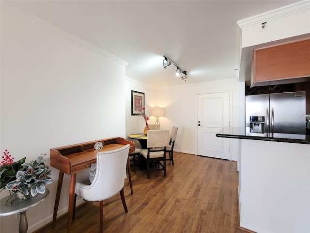 dining room with crown molding, rail lighting, and hardwood / wood-style flooring