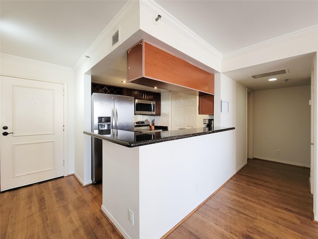 kitchen featuring kitchen peninsula, hardwood / wood-style floors, stainless steel appliances, and ornamental molding