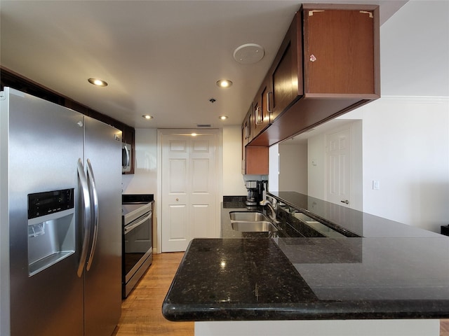 kitchen featuring kitchen peninsula, sink, stainless steel appliances, and light wood-type flooring