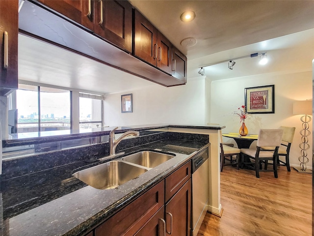 kitchen featuring dark stone countertops, dishwasher, sink, and light hardwood / wood-style flooring