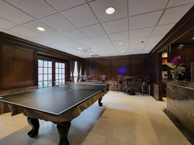 rec room featuring a paneled ceiling, crown molding, wooden walls, and french doors