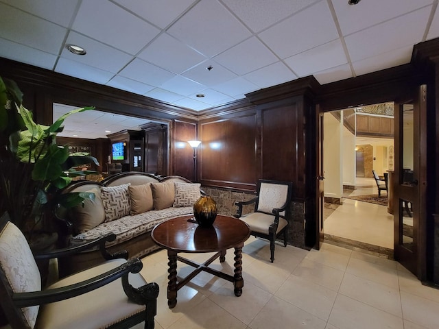 interior space featuring a paneled ceiling, wood walls, and ornamental molding