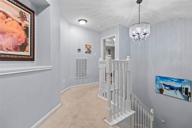 hallway with a notable chandelier and light carpet