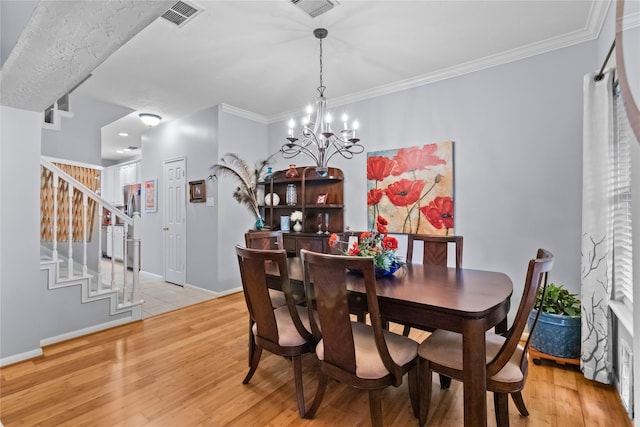 dining room with light hardwood / wood-style flooring, a chandelier, and ornamental molding