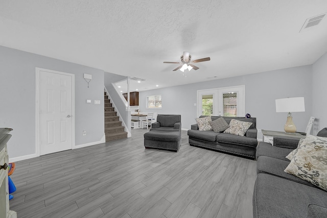 living room with ceiling fan, a textured ceiling, and french doors