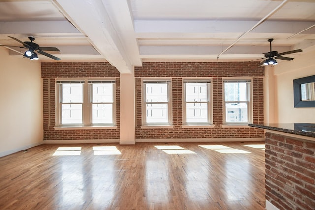 empty room featuring beamed ceiling and brick wall