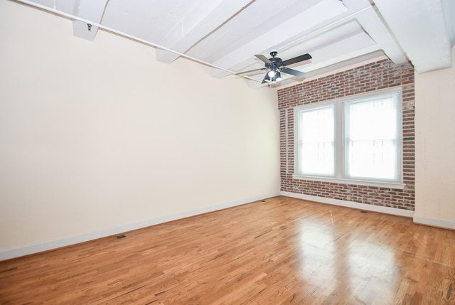 empty room with ceiling fan, brick wall, and light hardwood / wood-style flooring