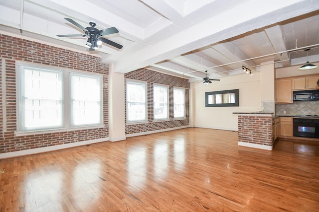 unfurnished living room featuring beam ceiling, light hardwood / wood-style floors, a wealth of natural light, and brick wall