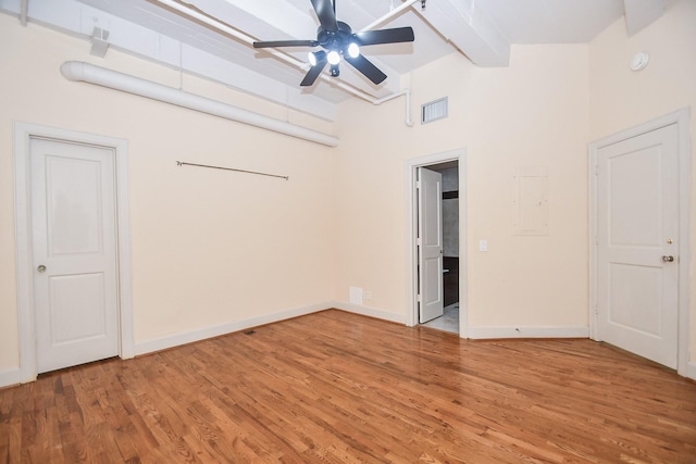 empty room featuring hardwood / wood-style floors, high vaulted ceiling, ceiling fan, and beam ceiling