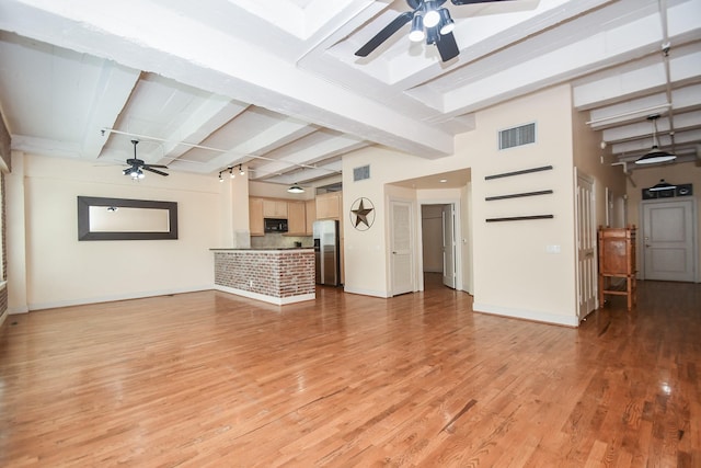 unfurnished living room featuring beamed ceiling and light wood-type flooring