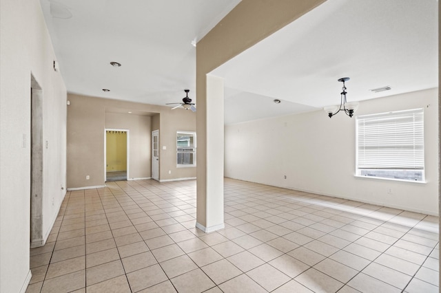 tiled empty room with plenty of natural light and ceiling fan with notable chandelier