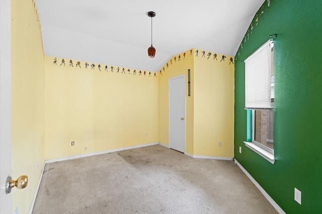 carpeted spare room featuring vaulted ceiling