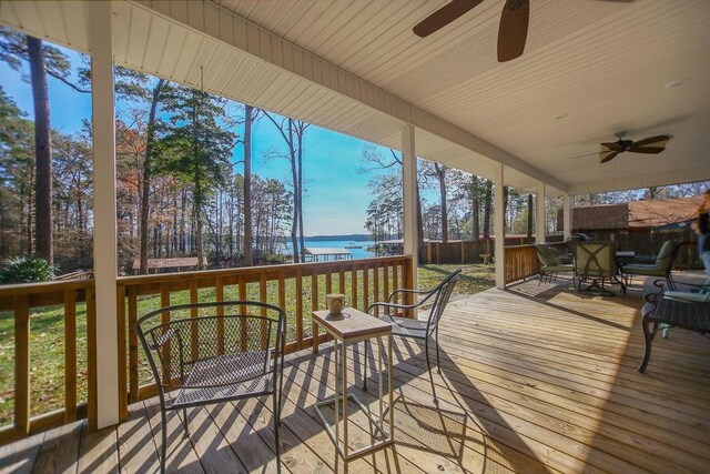 deck with a water view and ceiling fan