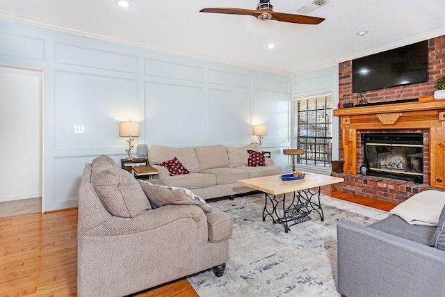 living room featuring light wood-type flooring, ornamental molding, and a fireplace