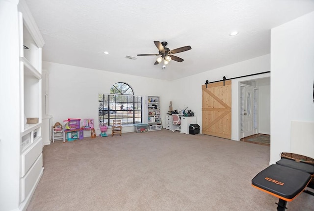 game room featuring a barn door, ceiling fan, and carpet