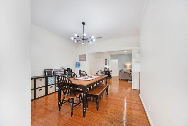 dining space with light wood-type flooring, ornamental molding, and a chandelier