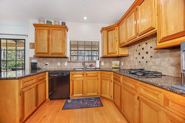 kitchen with decorative backsplash, light wood-type flooring, sink, dark stone countertops, and dishwasher