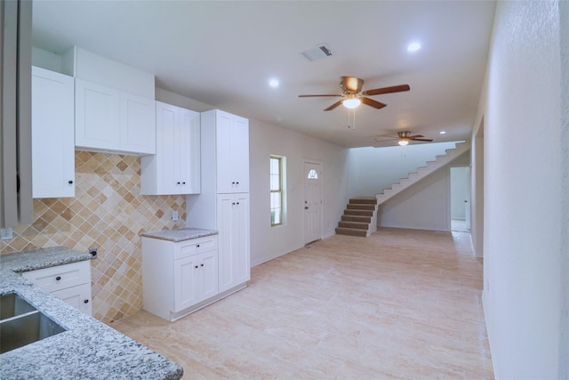 kitchen with white cabinets, tasteful backsplash, and light stone counters