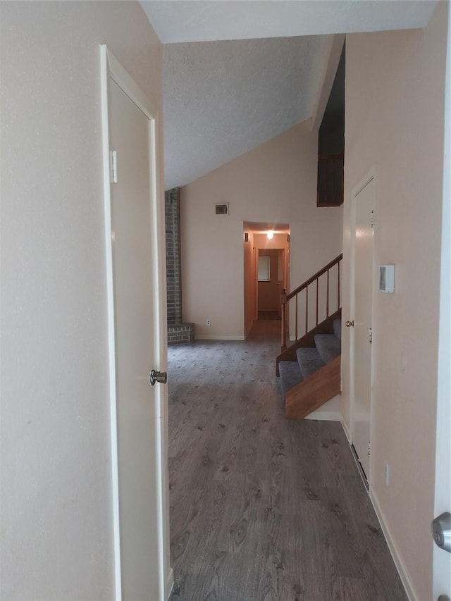 hall with lofted ceiling, a textured ceiling, and dark wood-type flooring