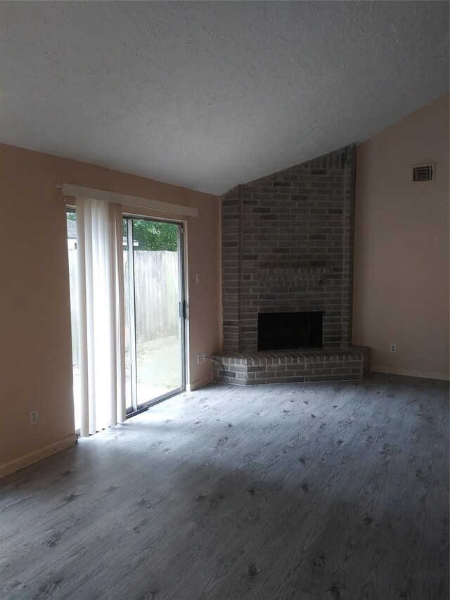 unfurnished living room featuring a fireplace, a textured ceiling, carpet floors, and lofted ceiling