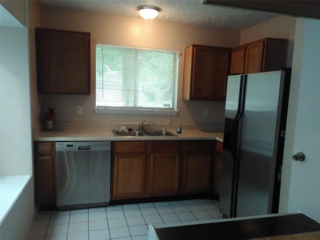 kitchen featuring a textured ceiling, light tile patterned floors, sink, and appliances with stainless steel finishes