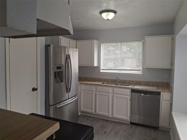 kitchen with white cabinets, light wood-style flooring, a sink, and appliances with stainless steel finishes