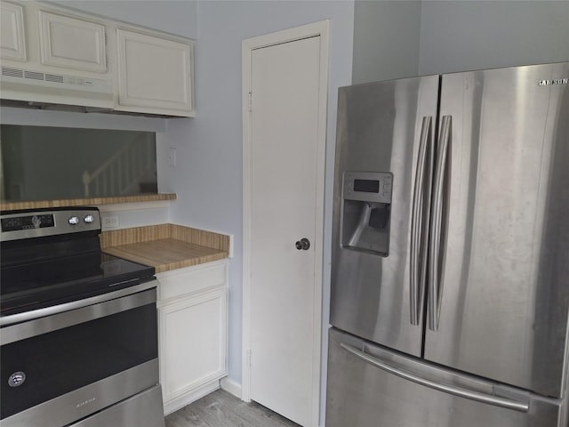 kitchen with white cabinets, light wood finished floors, light countertops, under cabinet range hood, and appliances with stainless steel finishes